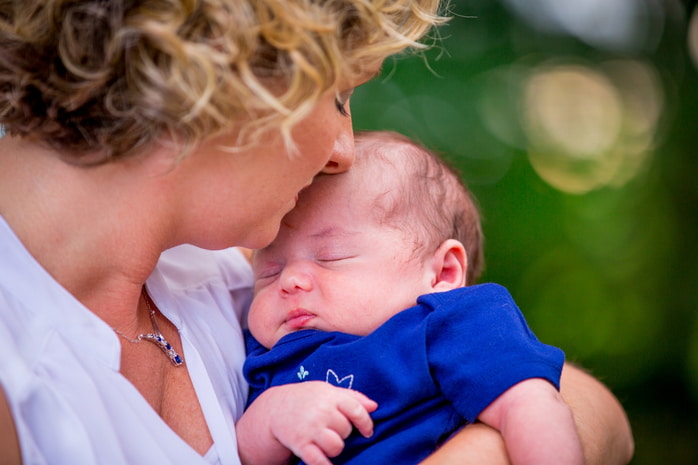 Adorable baby looking up with a curious expression during an outdoor family photo.