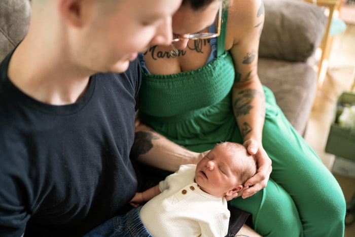 Husband and wife cuddling their newborn.