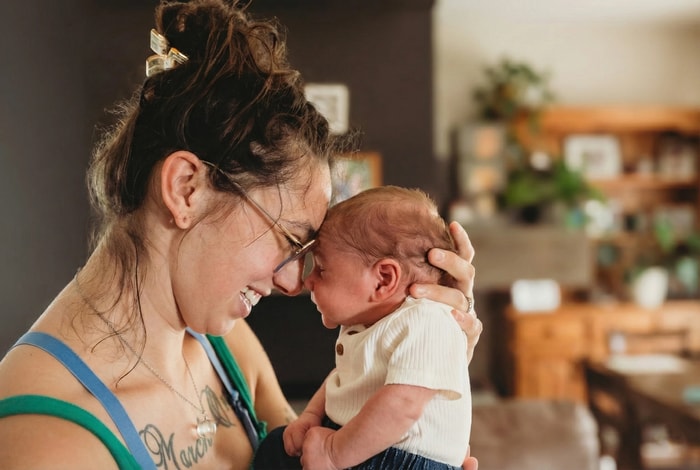 Mom cuddling her newborn baby in natural light.