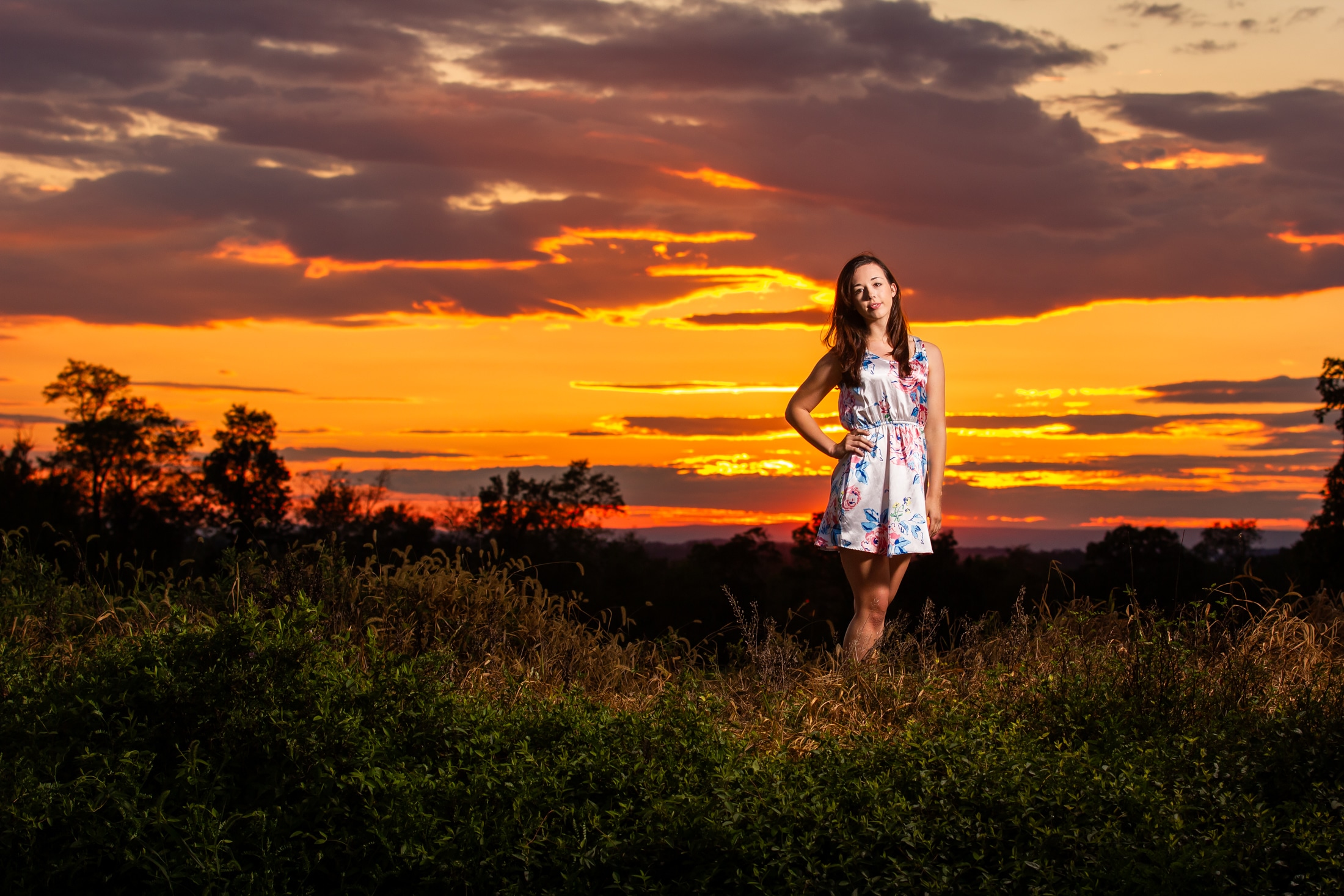 Senior girl looks at camera and smiles in golden sun