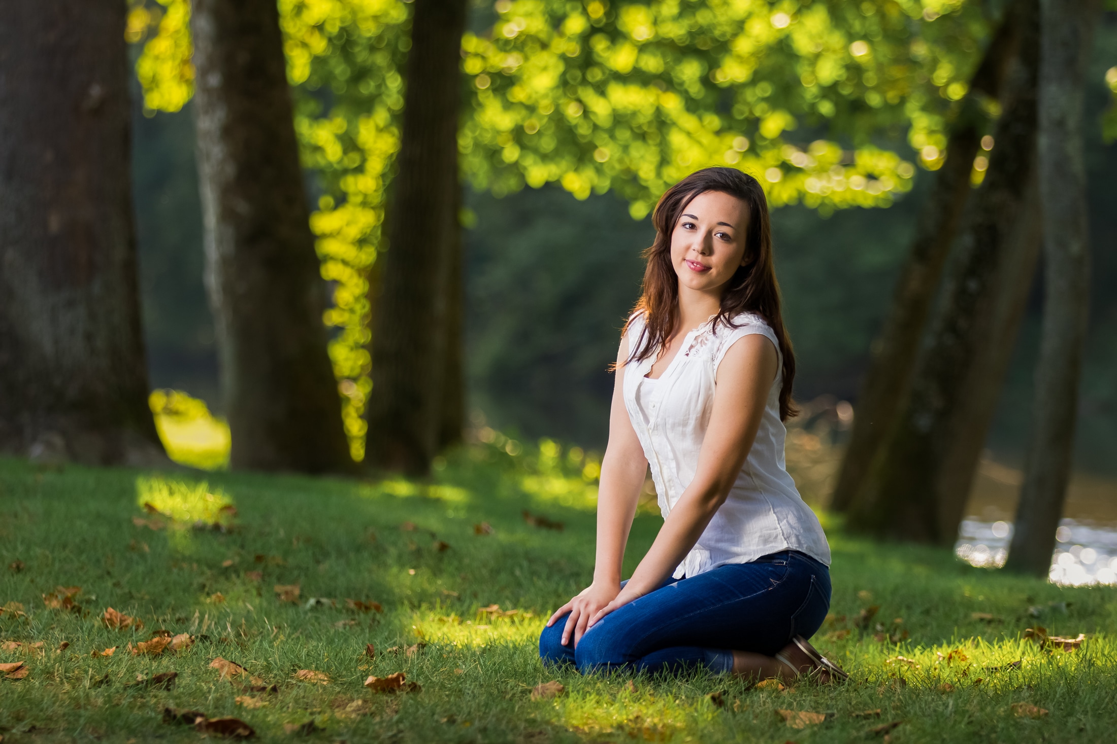 Senior girl looks at camera and smiles in golden sun