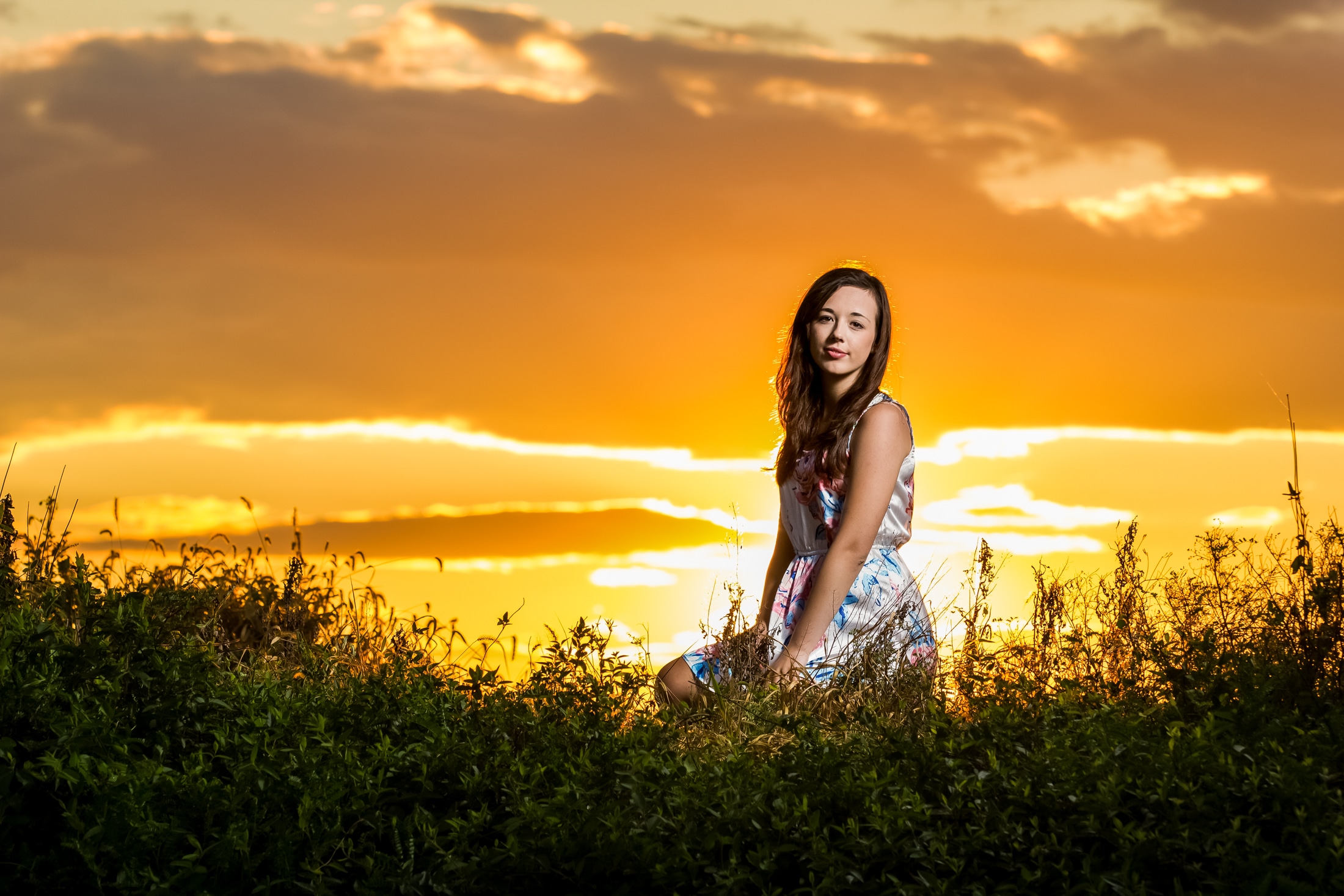Senior girl looks at camera and smiles in golden sun